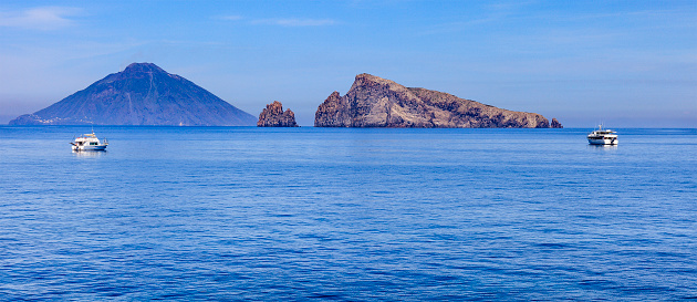 Lisca Bianca are rocks off the island of Panarea. On the background you can see the island of Stromboli. Aeolian archipelago, Sicily, Italy.