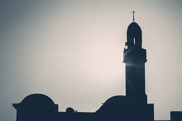 Mosque in Dubai, UAE A Mosque in Dubai with tall Minarets. Minaret also known as Goldaste or Minar. "lighthouse", is a distinctive architectural feature of mosques, generally a tall spire with a conical or onion-shaped crown, usually either free-standing or taller than associated support structure. The basic form of a minaret includes a base, shaft, and gallery. Styles vary regionally and by period. Minarets provide a visual focal point and are used for the call to prayer (azān). Toned image of Mosque Minaret with silhouette of shrubs in the foreground. azan stock pictures, royalty-free photos & images