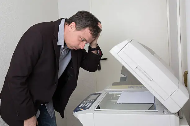Stressed man in front of a copy machine isolated