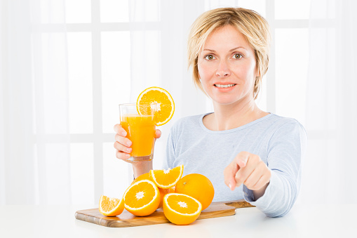 Woman with oranges on plank looking to the camera. 
