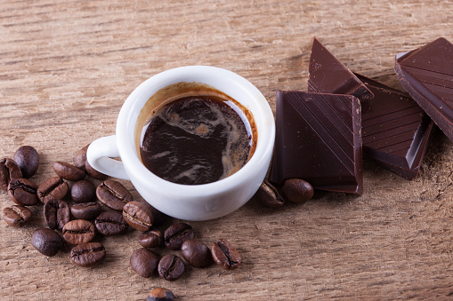 Cup, coffee beans, chocolate on a wooden Board close up background