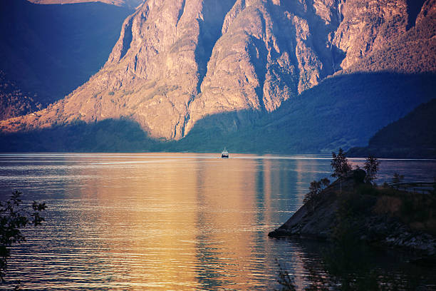 Evening sunlight and shadows of fjord cliffs with reflection in water