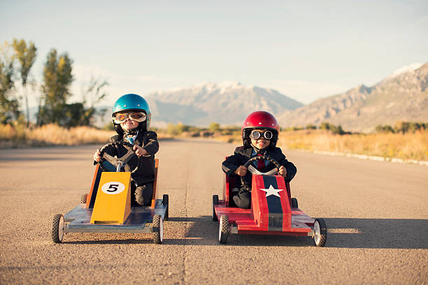 joven negocio muchachos en trajes de carreras de coches de juguete - car child teamwork sports race fotografías e imágenes de stock