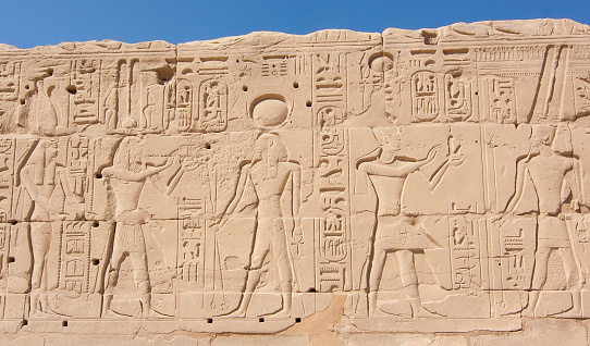 egyptian Engraved sand Wall representig human and gods figures an hieroglyphs outside Temple of Karnak Luxor .