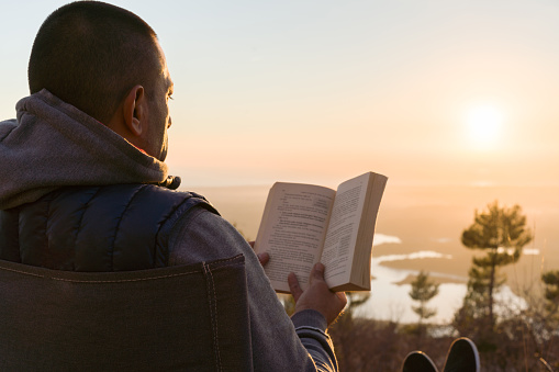 A man reading against sunset.