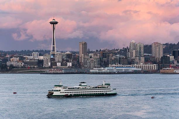 Seattle Skyline A ferryboat crosses Elliott Bay in front of the Seattle skyline and the historic Space Needle which is a leftover from the 1962 World's Fair during a lovely sunset. ferry photos stock pictures, royalty-free photos & images
