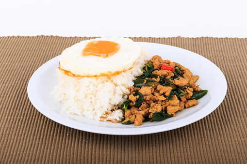 Rice topped with stir-fried chicken, basil and fried egg, fried stir basil with minced chicken on white background (Isolated Background)