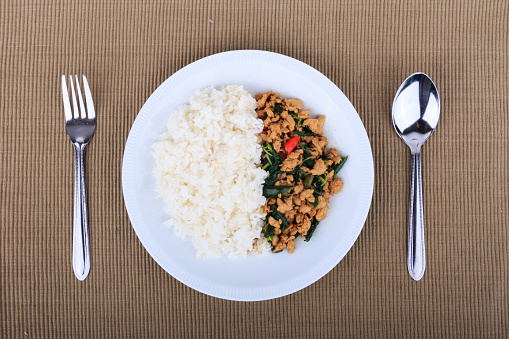 Rice topped with stir-fried chicken, basil and fried egg, fried stir basil with minced chicken on white background (Isolated Background)