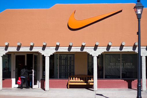 Santa Fe, USA- January 29, 2016: A Nike factory outlet shop in Santa Fe, NM, with customers entering. The store, with the Nike swoosh logo, is constructed in the typical Pueblo adobe architectural style of New Mexico.