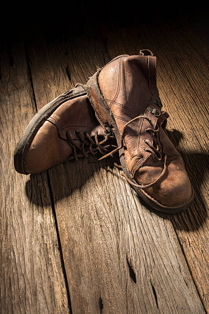 istock Pair of old used boots on rustic wood board 507301342