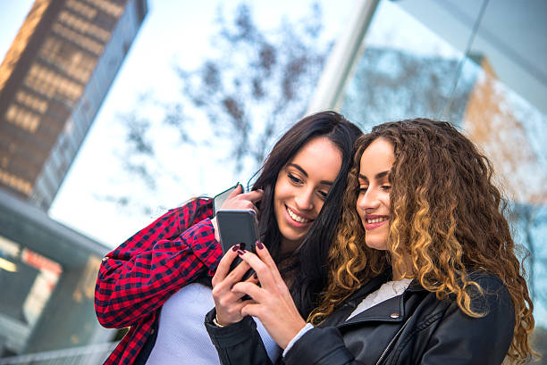 istock Two young women with smartphone on street 507302102