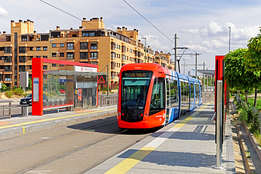 Madrid, Spain - September 5, 2015: Metro Ligero de Madrid (ML) tram operating on Line ML-1 stops adjacent to a modern medium density apartment building at Palas de Rey near the terminus at Las Tablas.  The light rail service on ML-1 offers convenient connections to Madrid Metro at both Las Tablas and Pinar de Chamartín.  Five of the nine stations on the 5.4km (3.4mi) line are underground. 