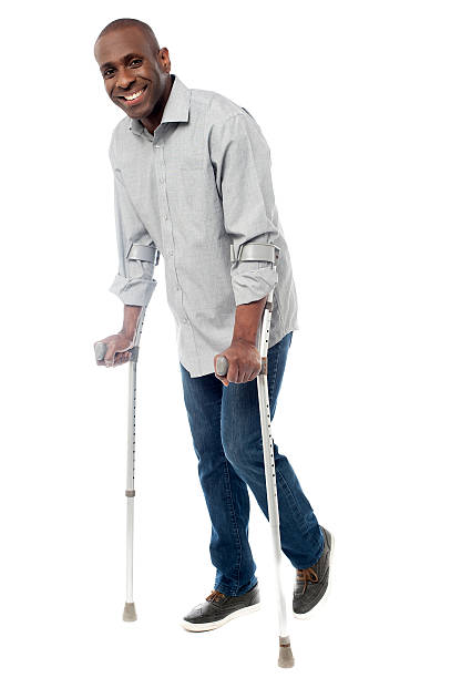 Man walking with crutches isolated on a white stock photo