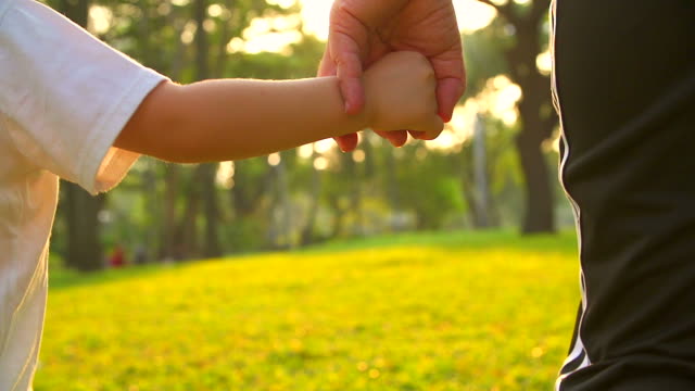 HD:Mother hold hand of his son walking in the park.