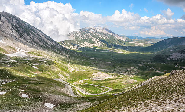 route sinueuse de motos de campo imperatore, abruzzes, italie - winding road sunlight field cultivated land photos et images de collection