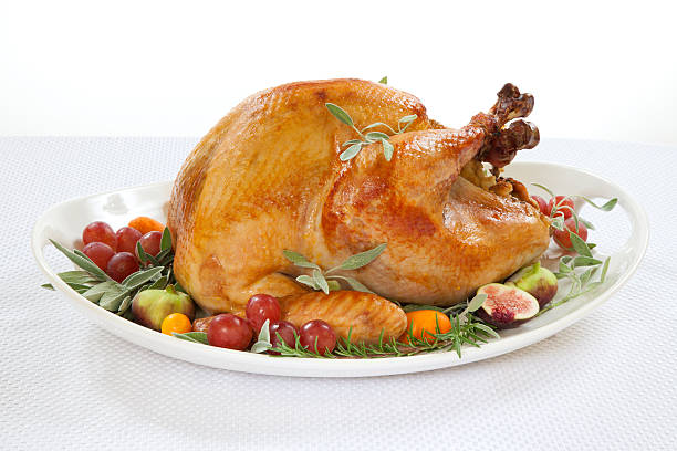 Roasted Turkey on tray over white Roasted turkey on tray garnished with red grapes, figs, kumquat, and herbs over white background roast turkey stock pictures, royalty-free photos & images