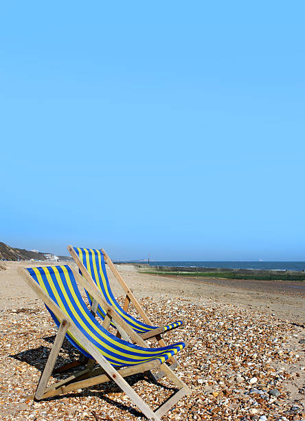 istock Blue and yellow striped deckchairs on English beach, poster, banner 507333863
