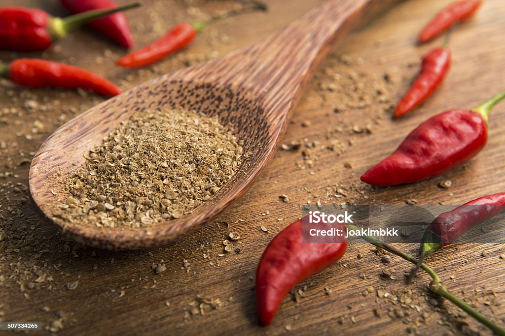 Wooden spoon of coriander on a table Spoon of coriander with a bowl of red chili peppers; selective focus on the powder. Asia Stock Photo