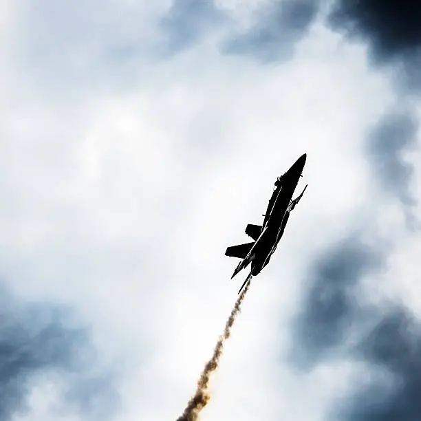 A US Navy F/A-18 aircraft in a steep climb. High contrast.