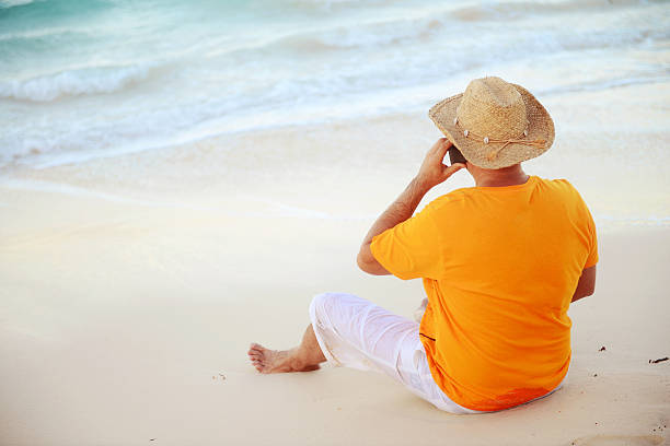 istock man sitting on the beach and talking on mobile phone 507360994