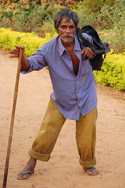Margao, India - November 20, 2007: Unidentidied lame tramp with a crook walks in the city park in the state of Goa in the late fall