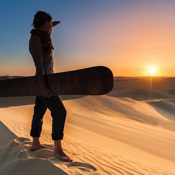 mujer joven sandboarding en el desierto del sahara, áfrica - great sand sea fotografías e imágenes de stock
