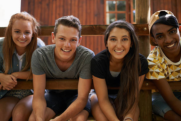 Making friends at summer camp Shot of a group of friends sitting together outside summer camp cabin stock pictures, royalty-free photos & images