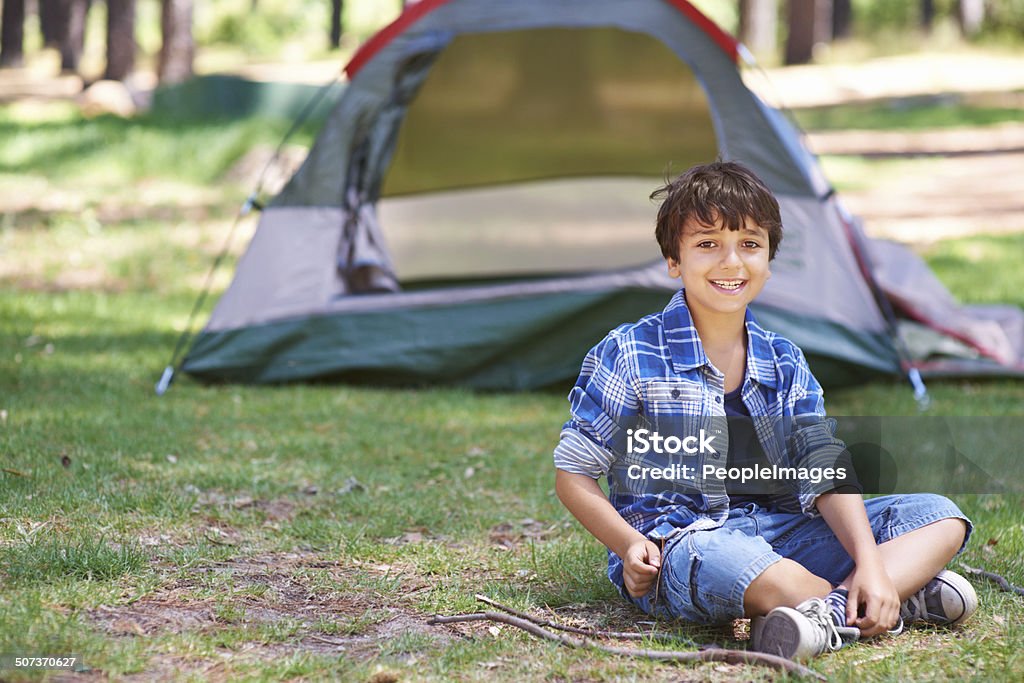 I love being outdoors! Portrait of a happy young boy sitting in front of a tent outdoors 10-11 Years Stock Photo