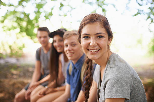 Fun times in the fresh air Portrait of a teenage girl sitting with her friends in the outdoors teenagers only stock pictures, royalty-free photos & images