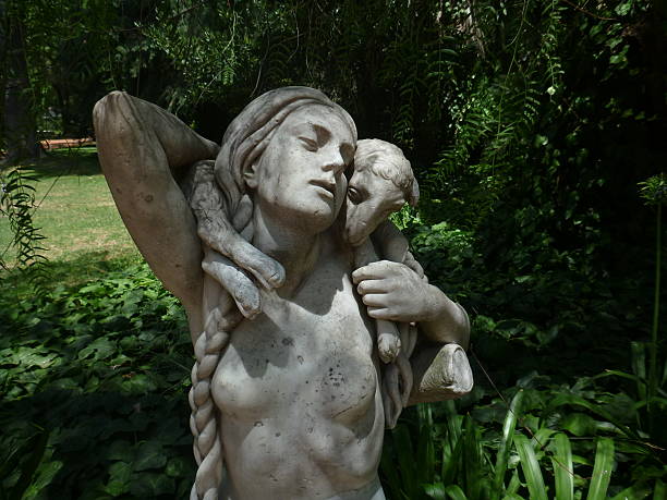 Beautiful marble sculpture of a naked lady with long plaited hair and a lamb on her shoulders, captured a park.