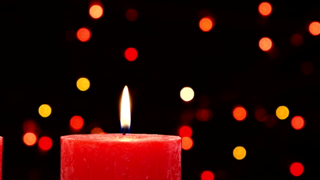 Top of two red candles with christmas decorations on black, bokeh, light, garland