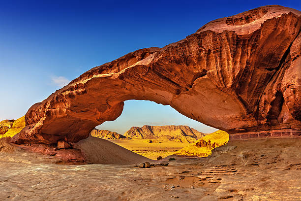 vista attraverso un arco roccioso nel deserto del wadi rum - wadi rum foto e immagini stock