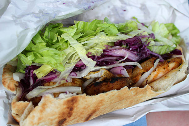 Traditional Turkish Kebab,Doner wrapped with flat bread,lavas on long plate at white surface.Served with cold drink