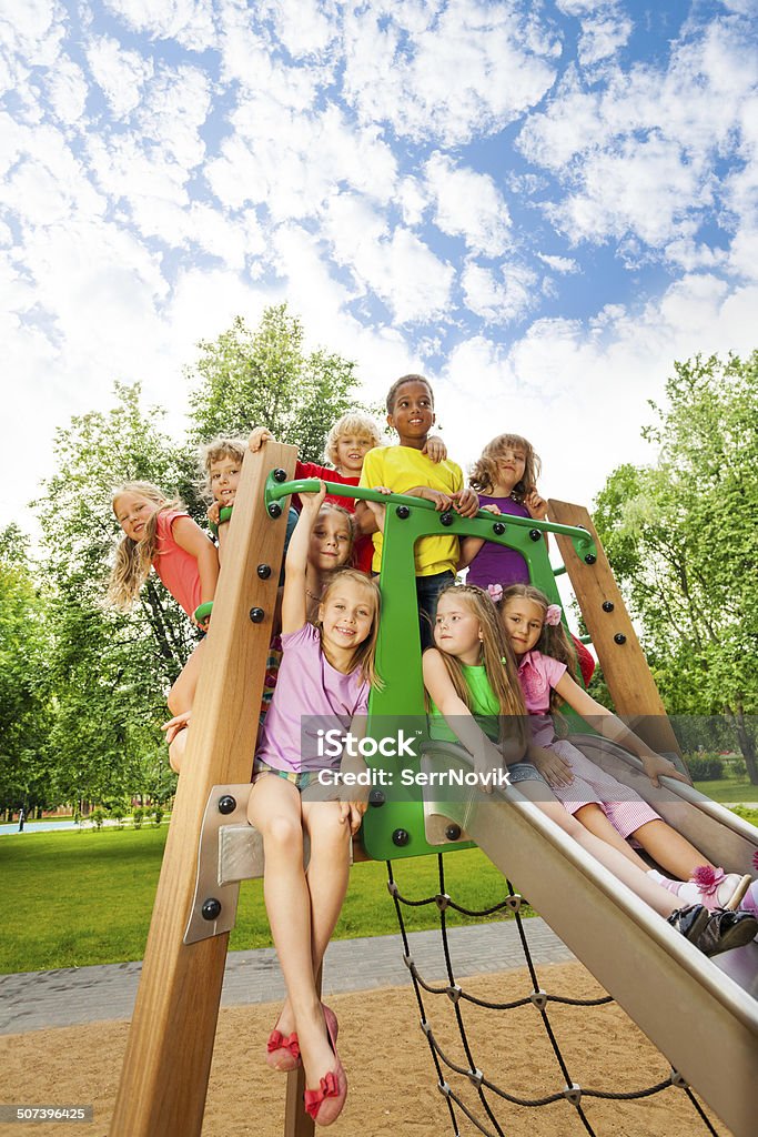 Group of friends together on a chute in summer Happy kids, group of friends, together on a chute of playground outside in summer Child Stock Photo
