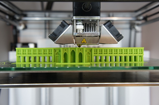 Bright green architectural model being 3D printed on glass printbed