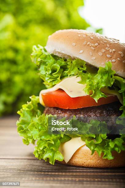 Cheeseburger Con Lechuga Y Tomate Cebolla En Un Nivel De Bun De Sésamo Foto de stock y más banco de imágenes de Alimento