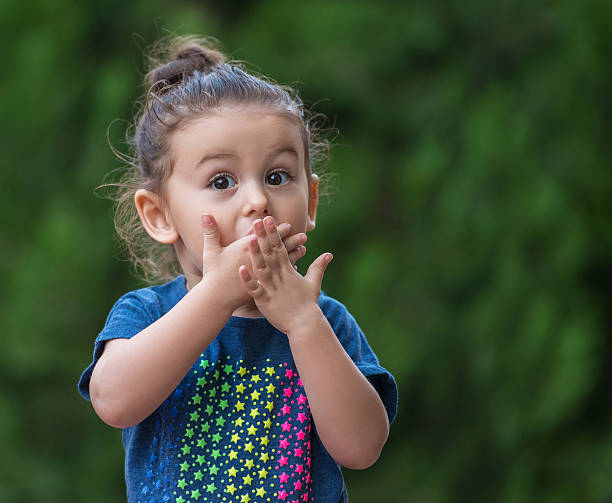 baby girl standing with a shocked face - hand voor de mond stockfoto's en -beelden