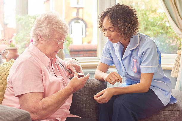 fall sensor pendant for senior woman a care nurse demonstrates to a senior woman how her panic pendant would work in the event of a fall or medical emergency. pendant stock pictures, royalty-free photos & images