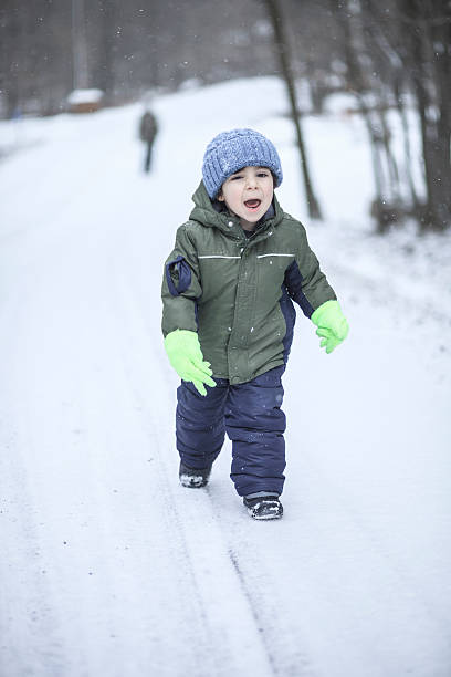 istock Little boy walking on the road under the snowfall 507400633