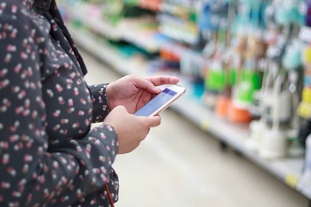 istock Woman using mobile phone while shopping in supermarket 507401190