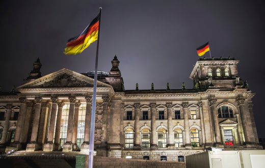 Rebuilt Reichstag Building. German flag waving in front of it.