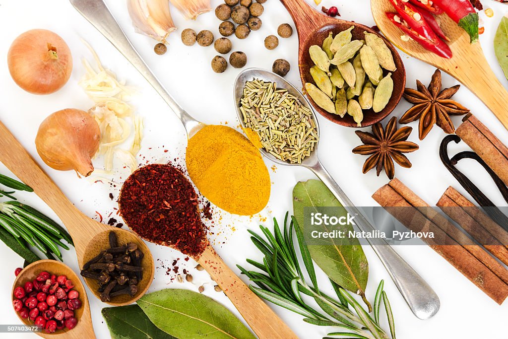 Different spices in spoons on white background. Different spices in spoons on white background. Top view. Cardamom Stock Photo