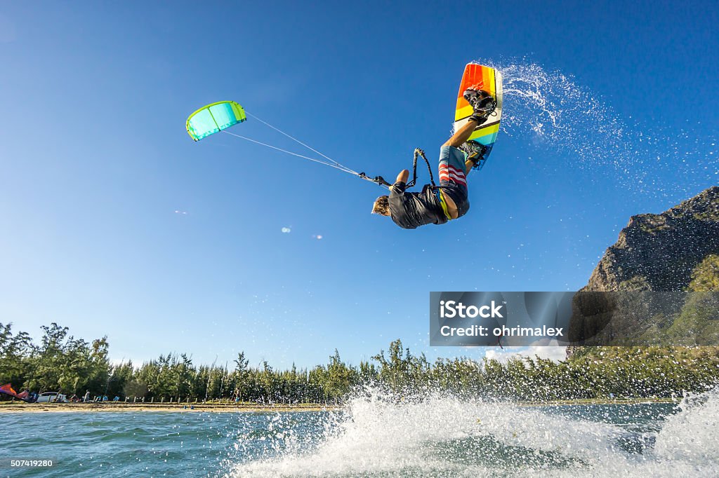 kiter's  trick professional kiter makes the difficult trick on a beautiful background of spray and beautiful mountains of Mauritius Kiteboarding Stock Photo