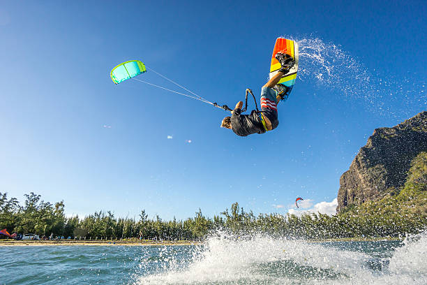 kiter's  trick professional kiter makes the difficult trick on a beautiful background of spray and beautiful mountains of Mauritius kiteboarding stock pictures, royalty-free photos & images