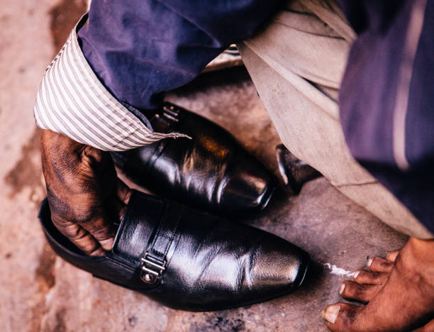 Close-up of dress shoes, striped socks and fashionable skinny trousers of businessman walking with his shadow on modern city sidewalk