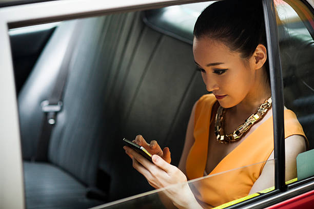 Young woman in taxi Young businesswoman in Hong Kong taxi, using smartphone. wealthy lifestyle stock pictures, royalty-free photos & images