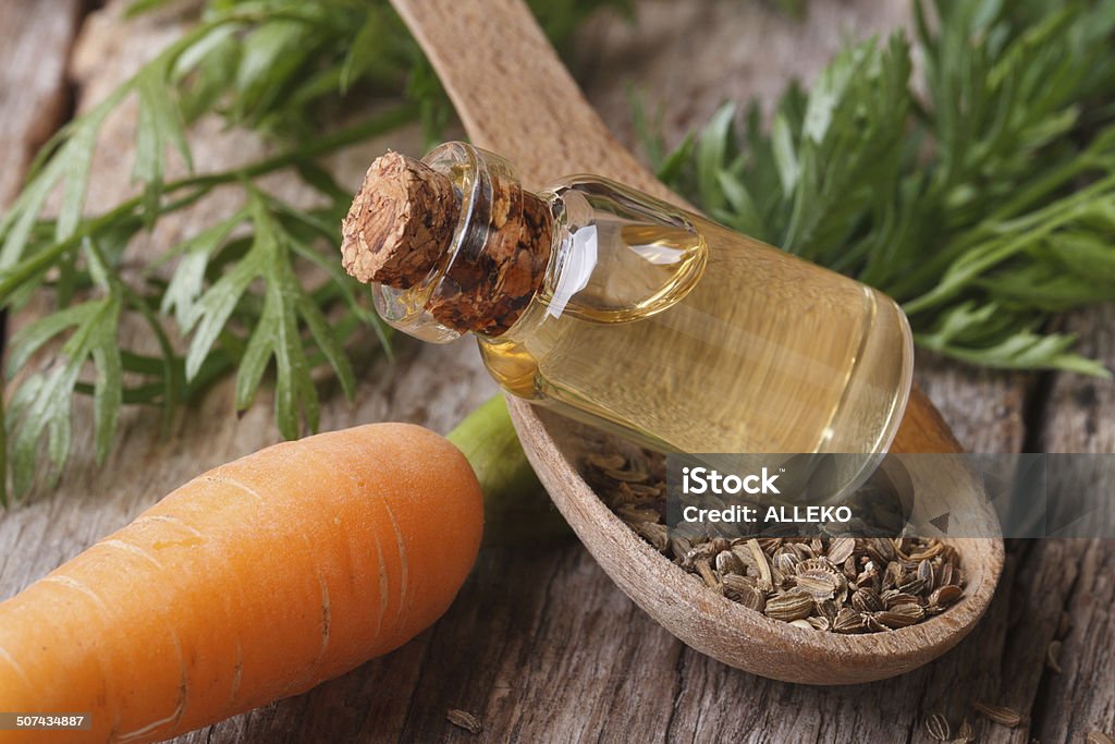 Useful carrot seed oil in glass bottle closeup horizontal. Useful carrot seed oil in glass bottle on the table close-up horizontal. Agriculture Stock Photo