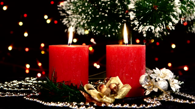 Two red candles with christmas decorations and tree on black, bokeh, light, garland, rotation