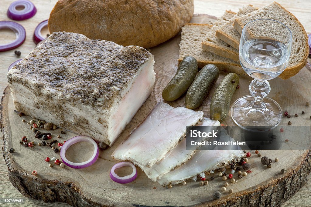 Sliced lard on a wooden desk Sliced lard on a wooden desk with cucumber, vodka and bread Lard Stock Photo