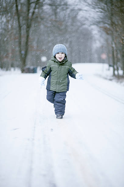 istock Little boy running on the road under the snowfall 507449963
